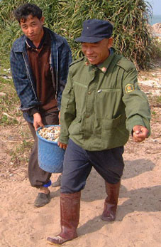 Two men with a bucket full of pebbles